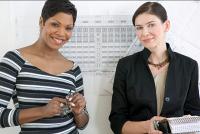Two women standing in front of an archetectural drawing.
